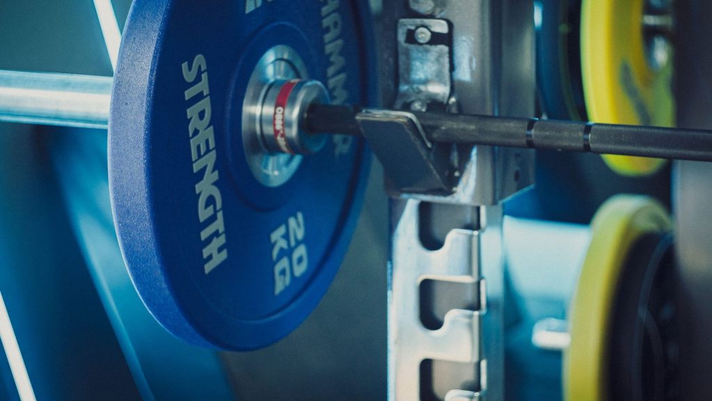 How many sets per muscle group per week: loaded barbell with weight plates in a gym