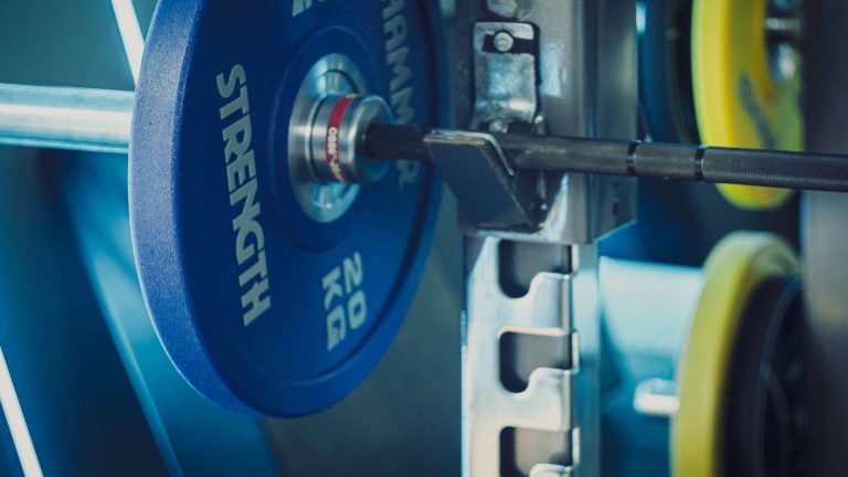 How many sets per muscle group per week: loaded barbell with weight plates in a gym